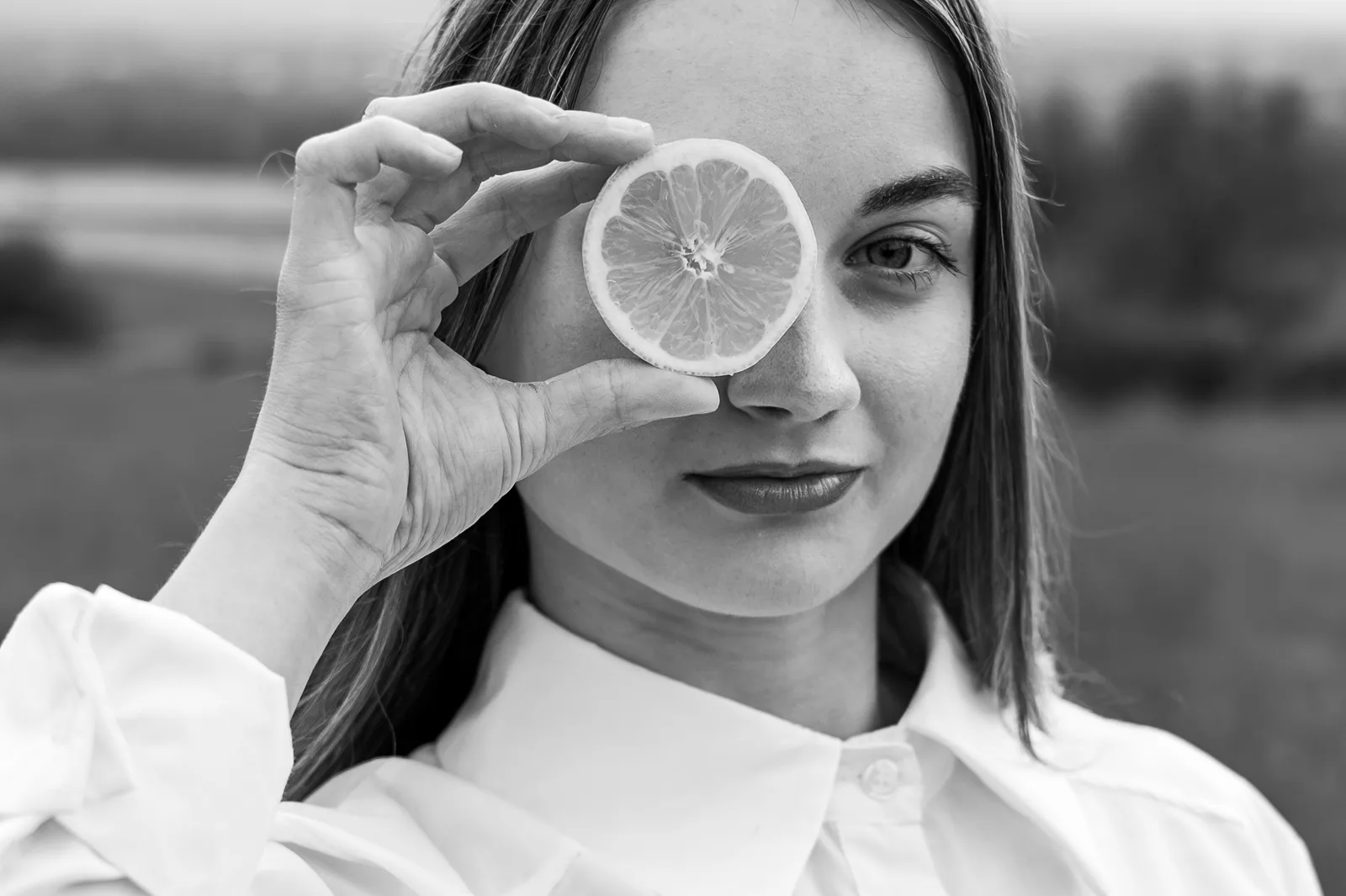 Dívka drží před okem plátek citronu